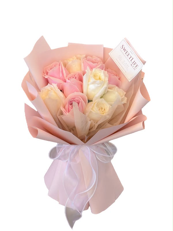 A 10-stem pink and white rose bouquet wrapped in blush pink paper with a white ribbon