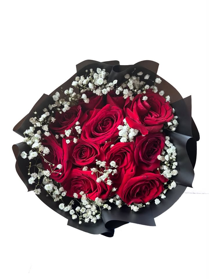 Red roses surrounded by baby's breath wrapped in black paper