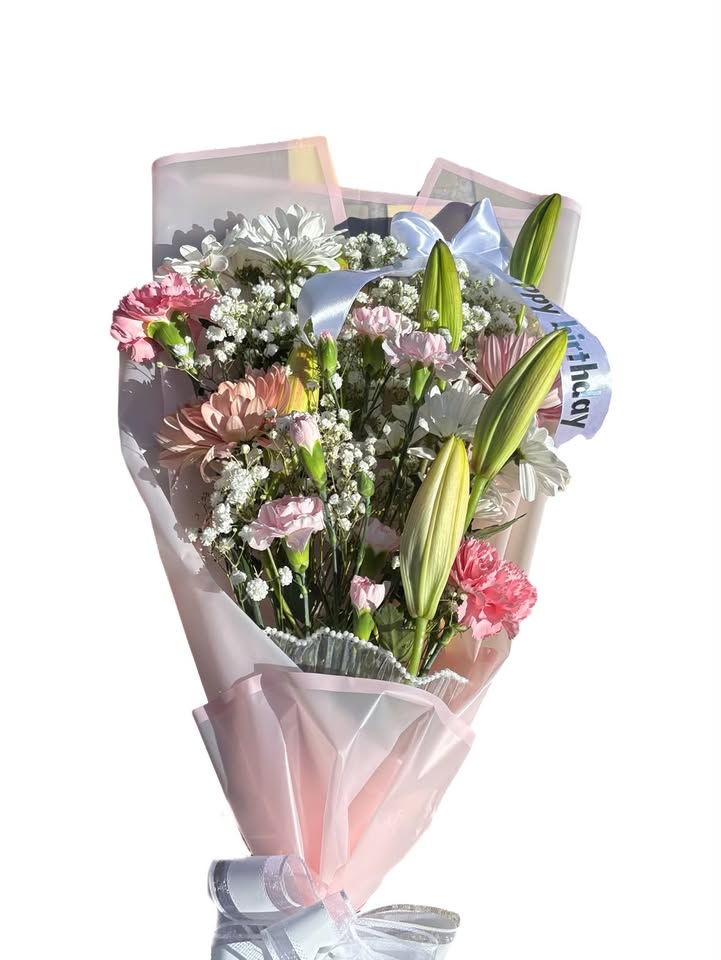 A pink birthday bouquet with lilies, carnations, baby's breath and a happy birthday ribbon